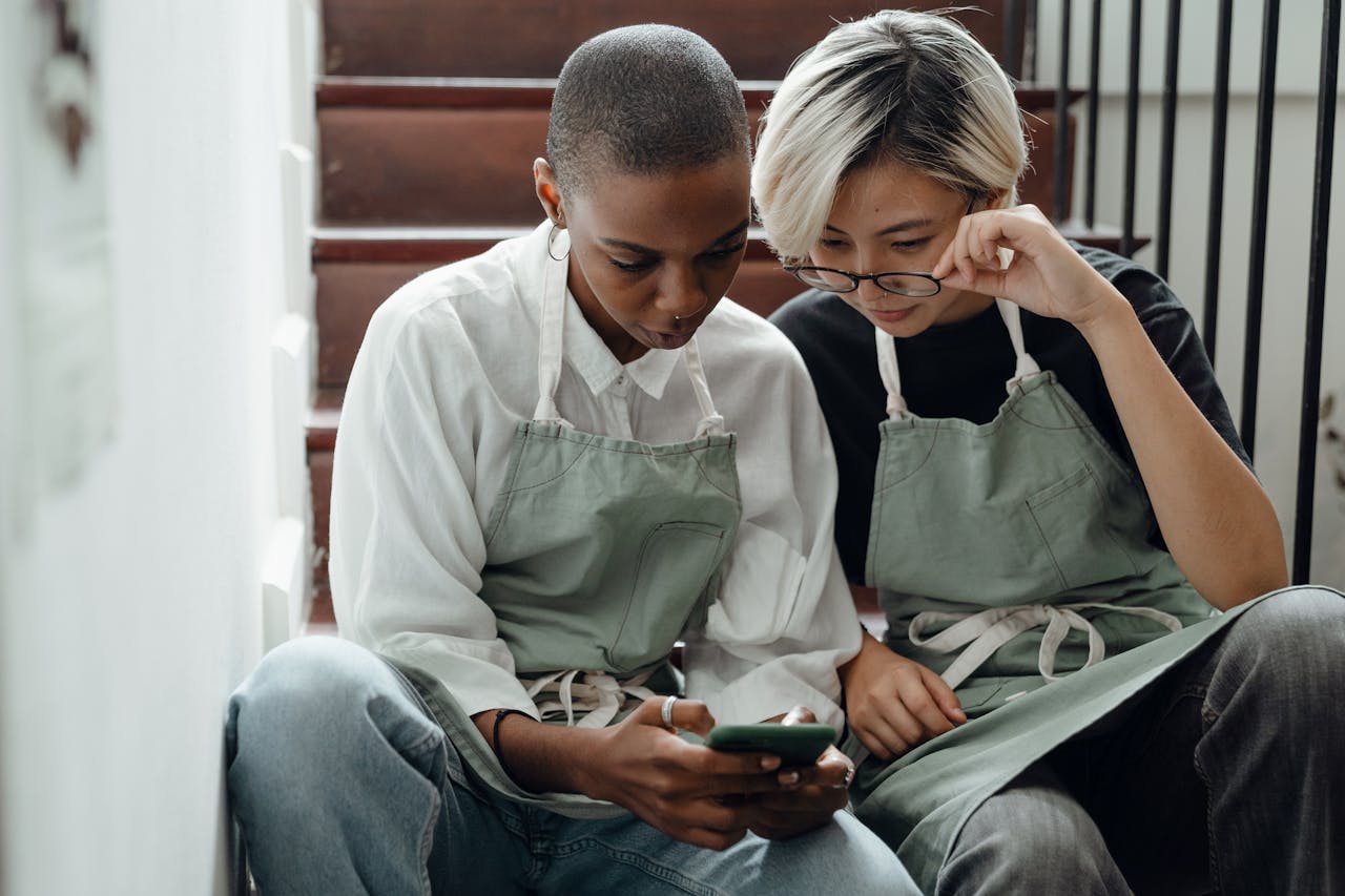 Concentrated young diverse girlfriends watching video on smartphone